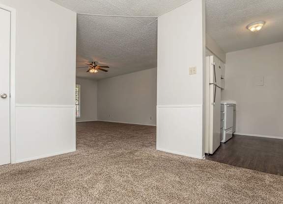 an empty living room with white walls and a ceiling fan