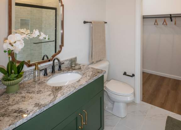 A bathroom with a green cabinet and a marble countertop.