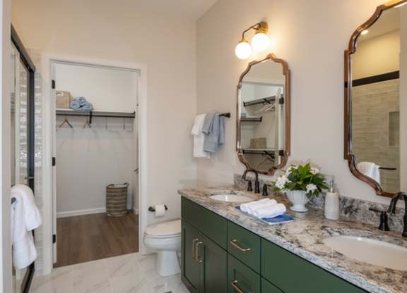 A bathroom with green cabinets and a marble counter.