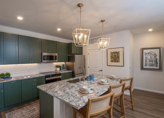 A kitchen with green cabinets and a marble countertop.