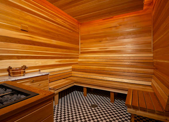 A wooden sauna with benches and a black and white checkered floor.