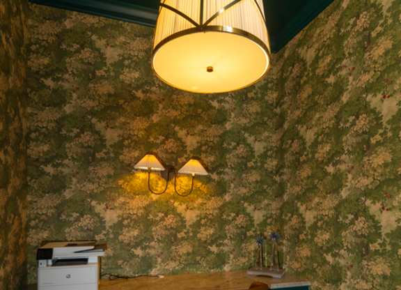 A room with a green wallpaper and a wooden chair.