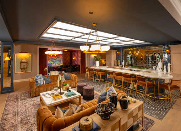 A cozy living room with a bar area in the background.