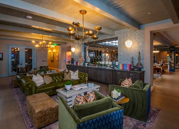 A large room with a green couch and a chandelier.