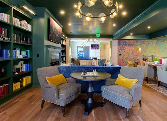 A room with a round table and chairs with yellow pillows.