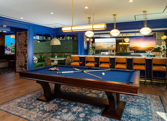 A pool table is in the middle of a room with a blue wall.