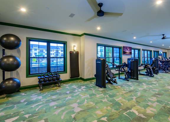 A gym with exercise equipment and a green floor.
