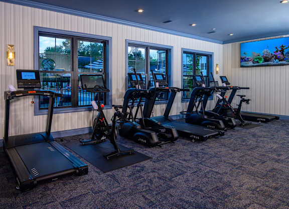 Fitness center with cardio equipment and screens at Fairmont Apartments, Westerville