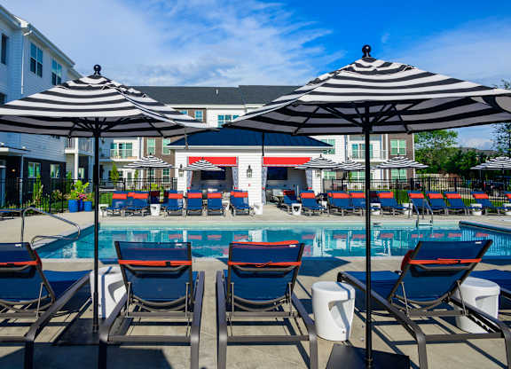 Resort style pool with striped umbrellas and lounge chairs at Fairmont Apartments, Westerville, Ohio