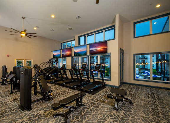 A gym with a variety of equipment including treadmills, elliptical machines, and weights.