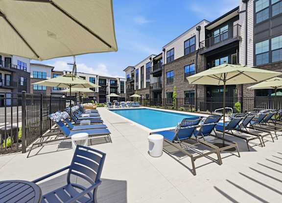 A sunny day at the pool with chairs and umbrellas.