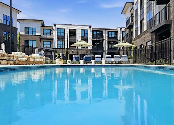 A swimming pool in front of a row of apartment buildings.