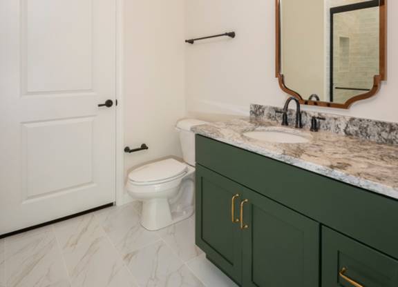 A bathroom with a white toilet and green cabinets.