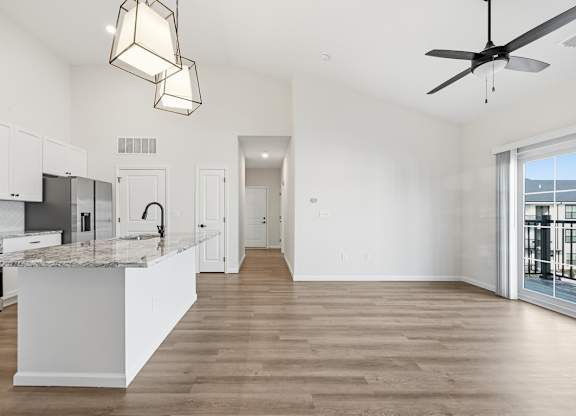 A modern kitchen with a marble countertop and a ceiling fan.