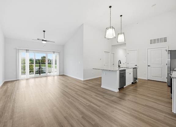 A spacious kitchen with white cabinets and a wooden floor.