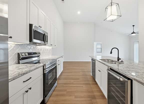 A modern kitchen with a marble countertop and stainless steel appliances.