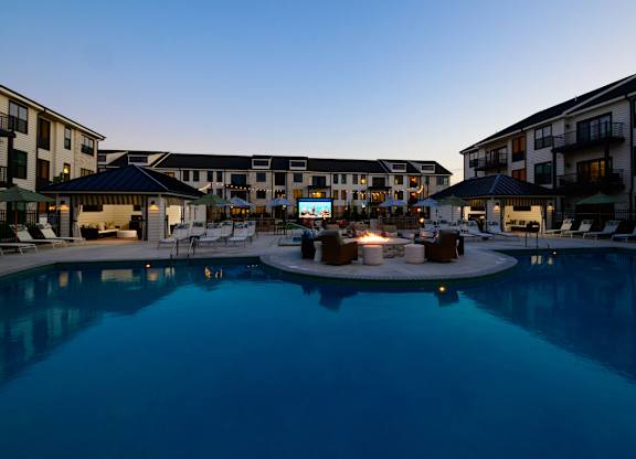 A swimming pool surrounded by apartment buildings at dusk.