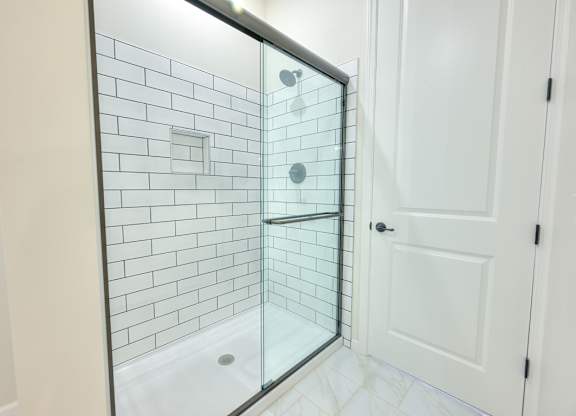 A white door is next to a glass shower stall.