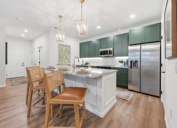 A kitchen with a white island and green cabinets.