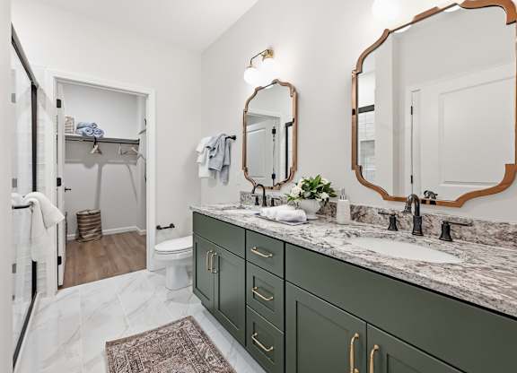 A bathroom with green cabinets and a marble countertop.