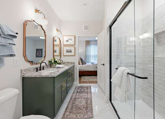 A bathroom with a green vanity and a glass shower stall.