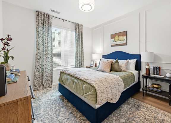 A bedroom with a bed, nightstand, and a window with curtains.