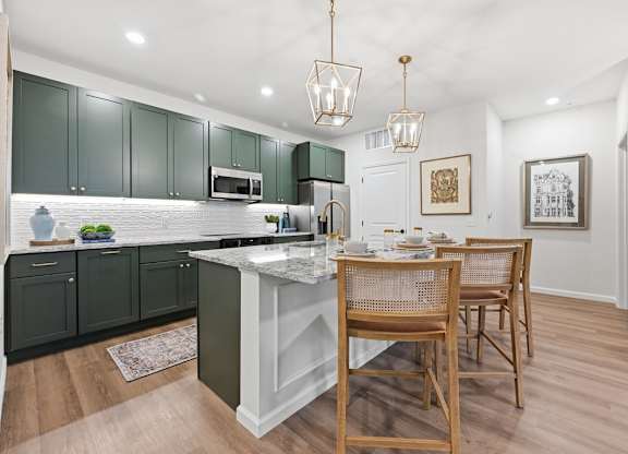 A kitchen with green cabinets and a white island.
