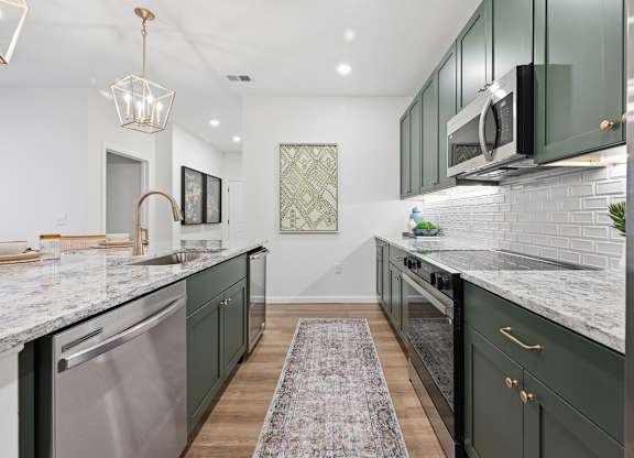 A kitchen with green cabinets and a marble countertop.