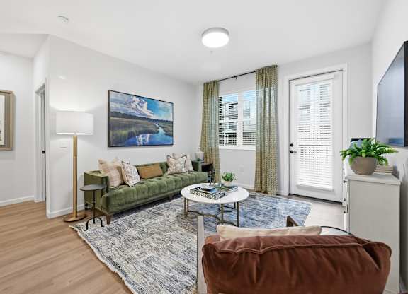 A living room with a green couch, a coffee table, and a painting on the wall.