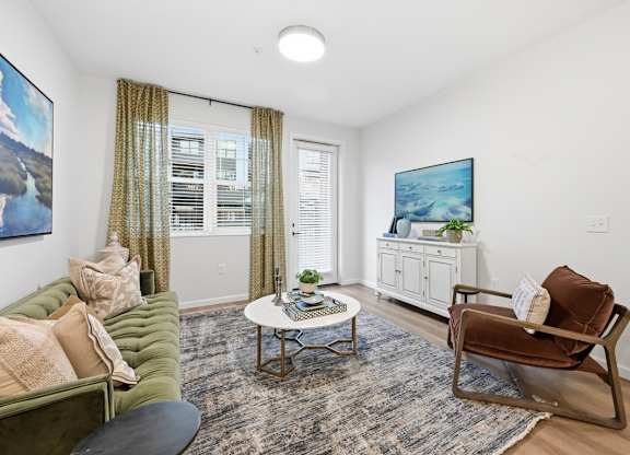 A living room with a green couch, a coffee table, and a painting on the wall.