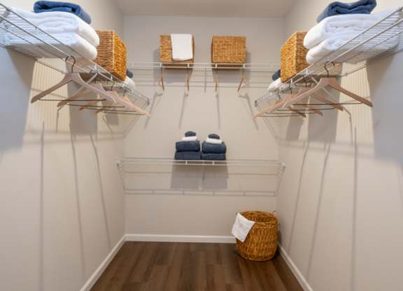 A laundry room with clothes on shelves and a basket on the floor.