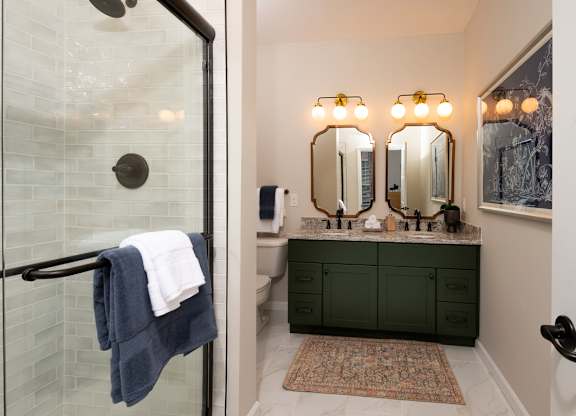A bathroom with a glass shower door and a green vanity.