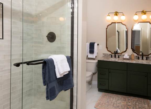 A bathroom with a glass shower door and a white towel hanging on it.