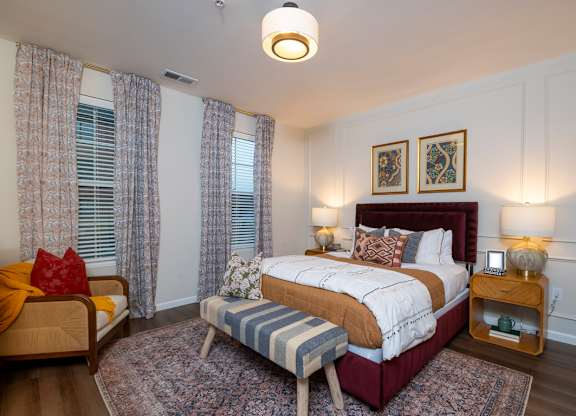 A bedroom with a large bed, a chair, and a bench.