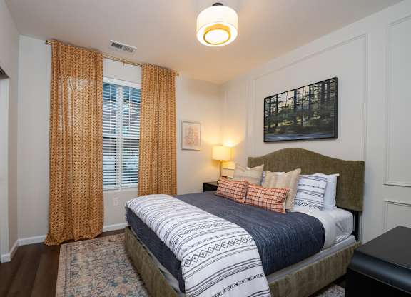 A bedroom with a large bed and a painting on the wall.