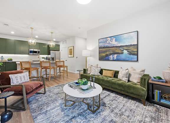A living room with a green couch, a coffee table, and a painting on the wall.