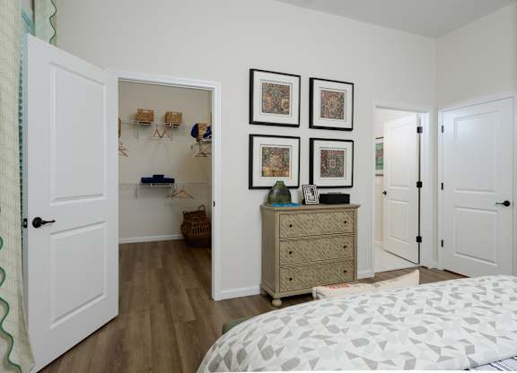 A bedroom with a white bed and a dresser with three drawers.