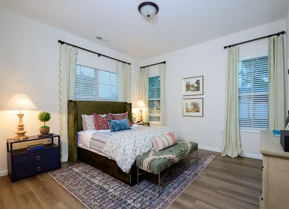 A bedroom with a large bed and a nightstand with a lamp.