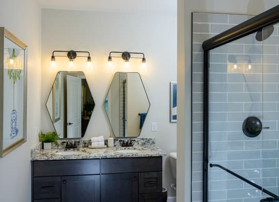 A bathroom with a marble countertop and a large mirror above it. at Fairmont Apartments, Westerville, 43081