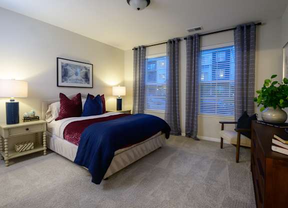 A bedroom with a bed, nightstands, and a plant. at Fairmont Apartments, Ohio