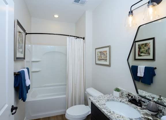 A bathroom with a white toilet, a sink, a bathtub, and a mirror. at Fairmont Apartments, Ohio