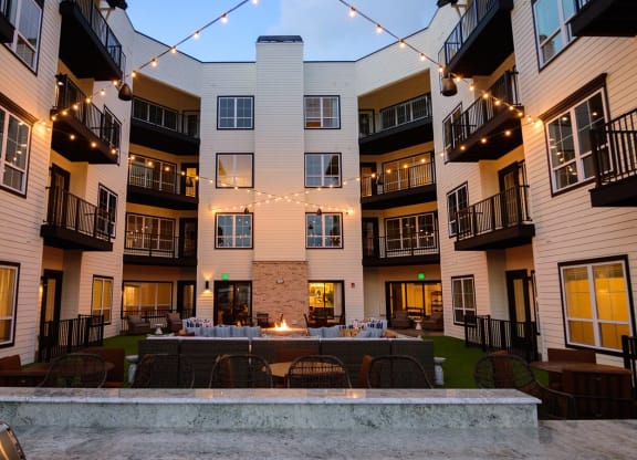 an outdoor patio with a firepit and string lights at the flats at big tex apartments in at Essex, Ohio, 43212