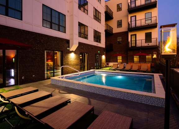 a pool with lounge chairs and umbrellas in front of an apartment building at Fairfax, Grandview, 43212
