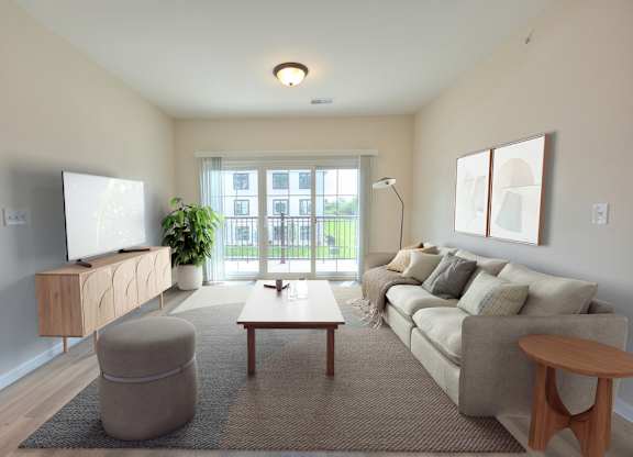 A living room with a grey sofa, a wooden coffee table, a grey ottoman, a wooden side table, a flat screen TV, a potted plant, and a window with a view of a building outside.