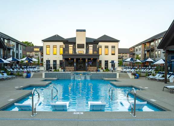 A large swimming pool in front of a building with a white and black exterior.