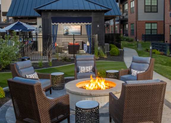 A fire pit surrounded by chairs in a garden setting.