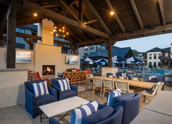 A patio with blue and white striped chairs and a fireplace.