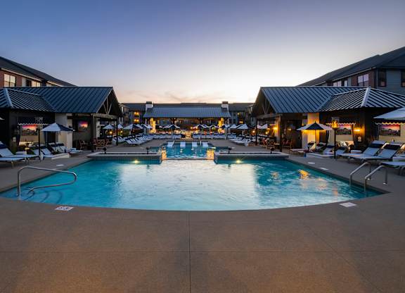 A large outdoor swimming pool surrounded by lounge chairs and umbrellas.