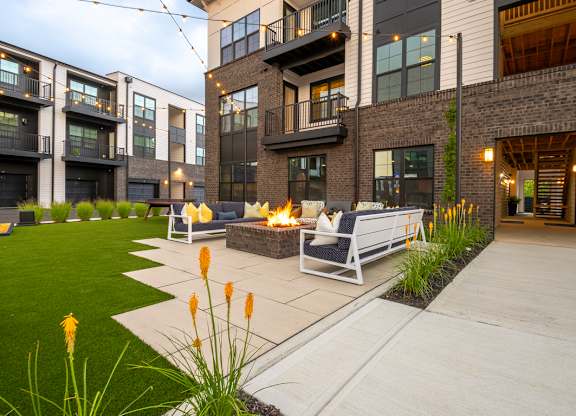 A modern outdoor seating area with a fire pit and chairs.