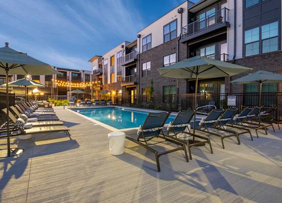 A pool surrounded by chairs and umbrellas.
